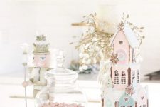 a pastel sweets table with pink and blue houses, pink candies in jars and touches of gold for a shiny look