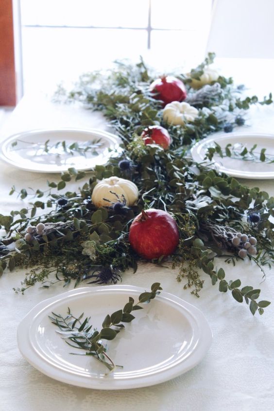 a pretty greenery table runner with pomegranates, white pumpkins, thistles and berries is amazing for Thanksgiving