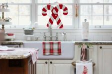 a red, white and green pompom garland, candy cane decor and plaid textiles for Christmas