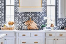 a refined formal white kitchen with shaker style cabinets, with gold touches for a chic feel and navy and white Moroccan tiles on the backsplash