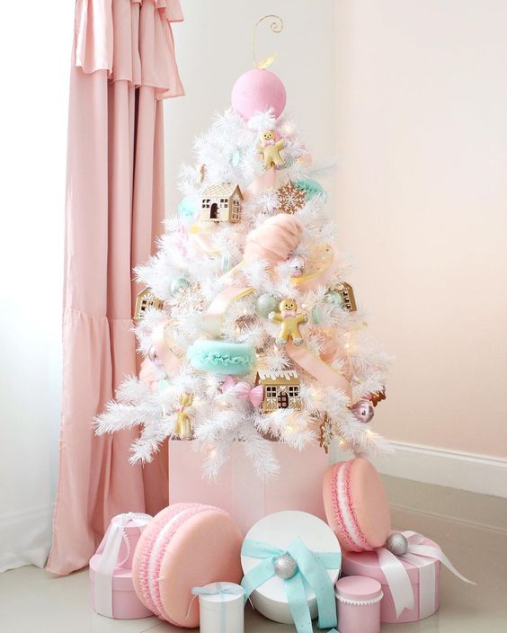 A small white Christmas tree decorated with pink, aqua, blush ornaments   houses, cookies, macarons and oversized ornaments looks amazing