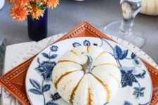 a stack of white, orange and blue and white plates and a blue vase with orange blooms for a chic Thanksgiving table