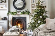 a stylish Christmas tree with silver ornaments, a stocking and a greeneyr garland with pinecones on the mantel