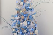 a white Christmas tree with bold blue bottle cleaners, seashells, starfish, twigs, corals and blue lights for a coastal Christmas space