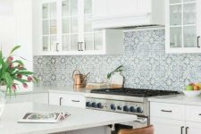 a white farmhouse kitchen with white stone countertops, a blue Moroccan tile backsplash and leather stools is amazing