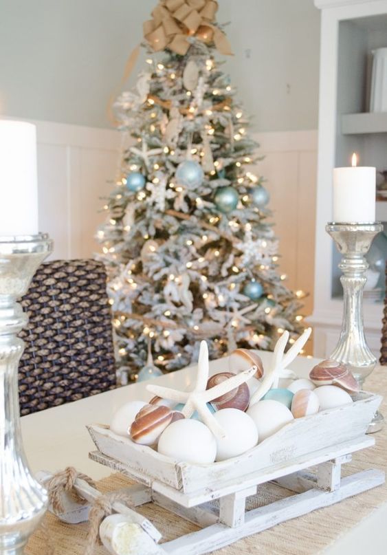 a whitewashed wooden sleigh with white ornaments, seashells and starfish is a lovely Christmas decoration