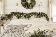 an evergreen wreath with pinecones, evergreen garlands with bulbs and plaid bedding for a farmhouse Christmas look