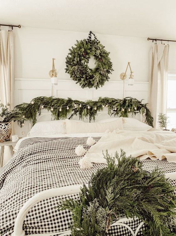 an evergreen wreath with pinecones, evergreen garlands with bulbs and plaid bedding for a farmhouse Christmas look