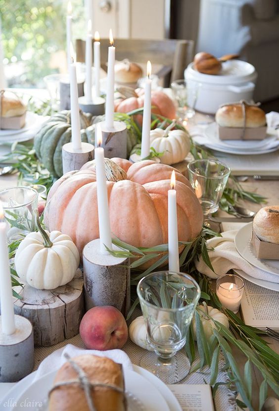 beautiful whitewashed pumpkins and peaches, greenery, white candles and tree stumps and candles around for Thanksgiving