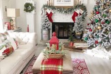 bright and fun Christmas decor with a flocked tree with gold, green and red ornaments, plaid pillows and a runner, red stockings, a flocked garland and flocked mini trees