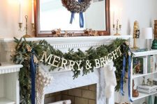 chic Christmas decor with a pinecone wreath, a fir garland with lights and blue ribbons, branches in a basket