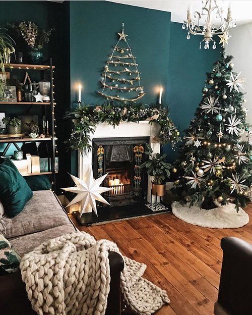 chic and glam Christmas decor with a tree decorated wiht white and grene ornaments a fir branch garland and a stick tree on the wall