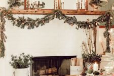 elegant rustic holiday decor with candles, a fir and bell garland, mini trees, branches in a bucket is very chic
