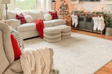 farmhouse Christmas decor with white stockings, red plaid pillows and red blankets, flocked wreaths and flocked Christmas trees plus candles