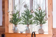 mini Christmas trees in burlap and metallic ornaments on the window for a holiday feel in the space
