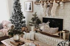 neutral knit stockings, a star garland, mini houses and candles, a greenery wreath and flocked Christmas trees