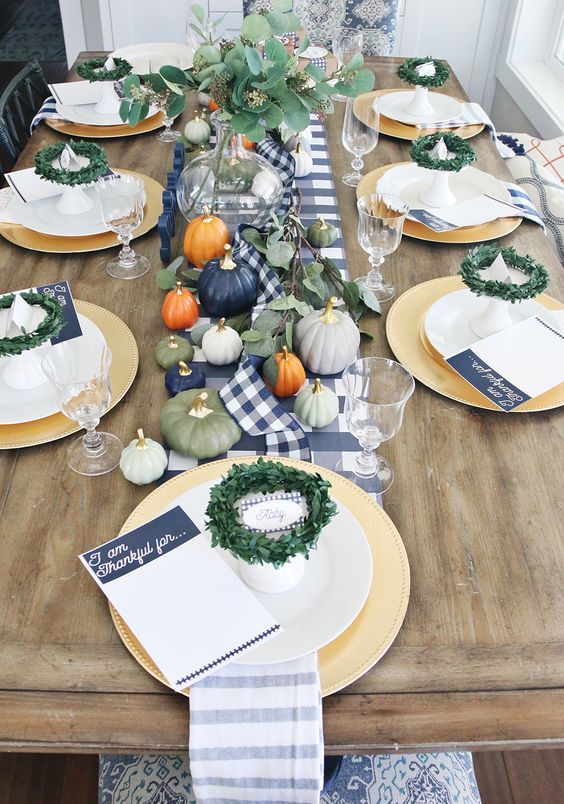 pastel pumpkins with gilded stems and greenery wreath and an arrangement for a modern Thanksgiving table