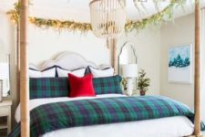 plaid bedding and evergreen and light garlands on the bed frame give a festive feel to the neutral bedroom