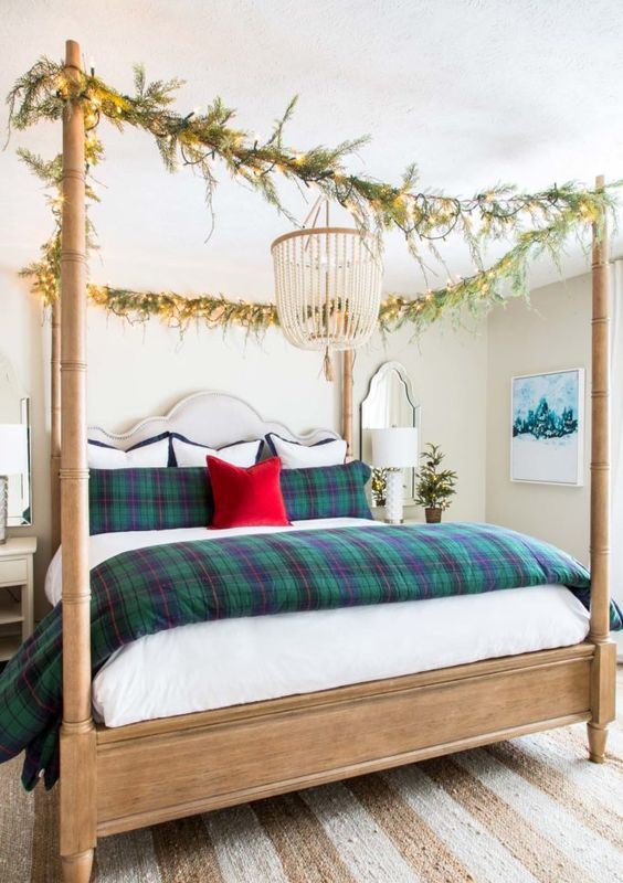 plaid bedding and evergreen and light garlands on the bed frame give a festive feel to the neutral bedroom