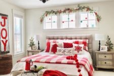 pompom garlands, an evergreen and berry branch, plaid red and white bedding and a red knit blanket for Christmas