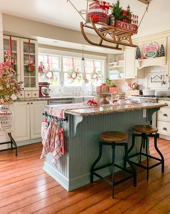 red, grey and white Christmas kitchen decor, a sleigh over the kitchen island, printed linens and a mini Christmas tree