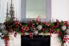 refined vintage mantel decor with greenery, plaid ribbons, oversized metal bells, vintage candleholders for Christmas