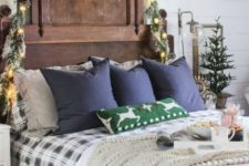 snowy evergreens, lights and pinecones, a mini Christmas tree, plaid bedding and a knit blanket for a festive feel