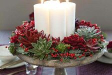 a Christmas centerpiece of a vintage bowl, succulents and evergreens, red succulents, berries and pillar candles is wow