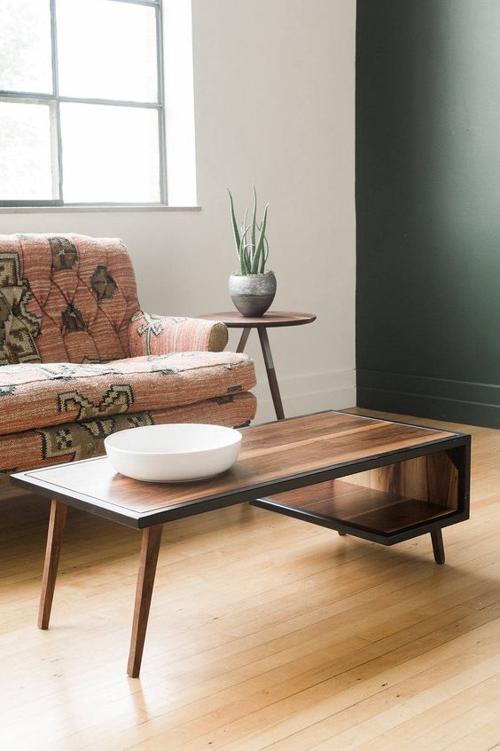 A beautiful mid century modern coffee table with a curved tabletop that makes an open storage compartment and with black edges