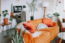 a boho living room with a modern orange sofa, potted plants, a macrame hanging, a small workspace in the corner is amazing