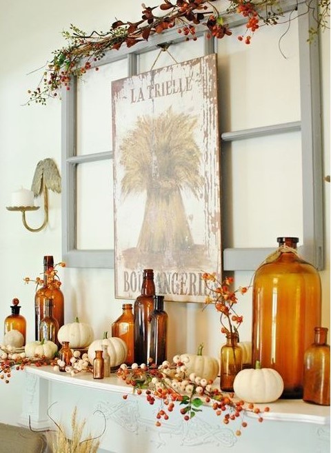 a bold fall rustic mantel with berries and greenery, white pumpkins, amber bottles, an artwork and berries over the mantel is cool