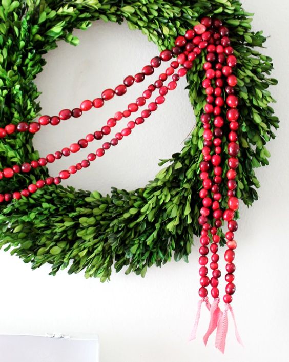 a boxwood Christmas wreath with cranberry garlands is a very cool and bold decor idea for the holidays