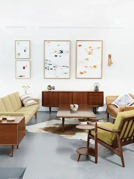 A bright mid century modern living room with mustard colored furniture and abstract paintings
