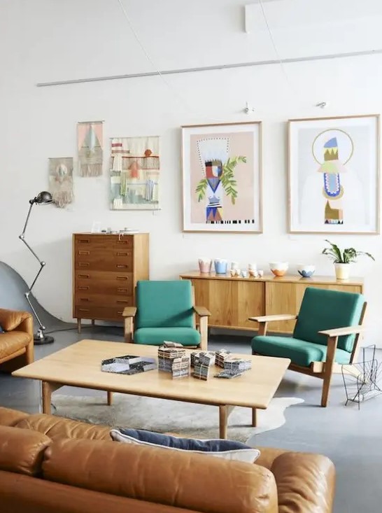 a bright mid-century modern living room with stained furniture, green chairs, an amber leather sofa, a low coffee table, a gallery wall and beautiful potted plants