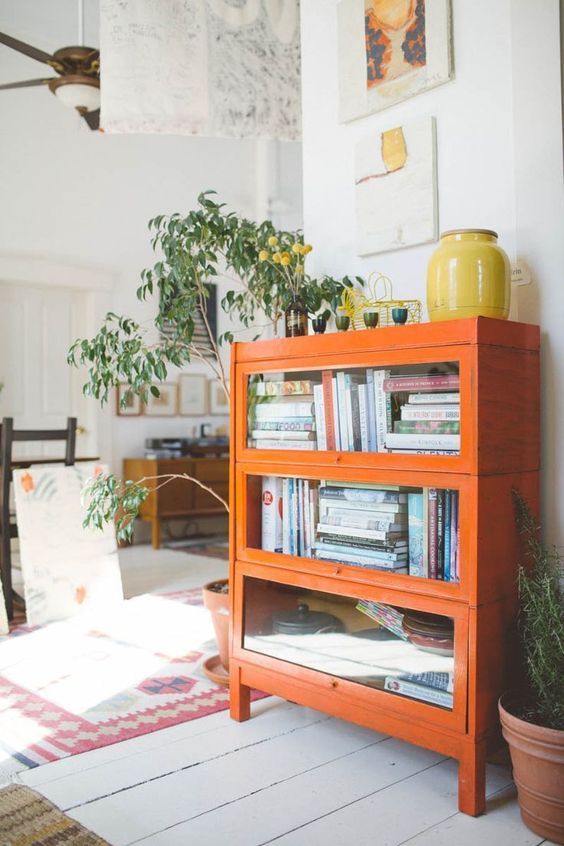 a bright orange bookcase with glass covered compartments is a great touch of color and a cute piece