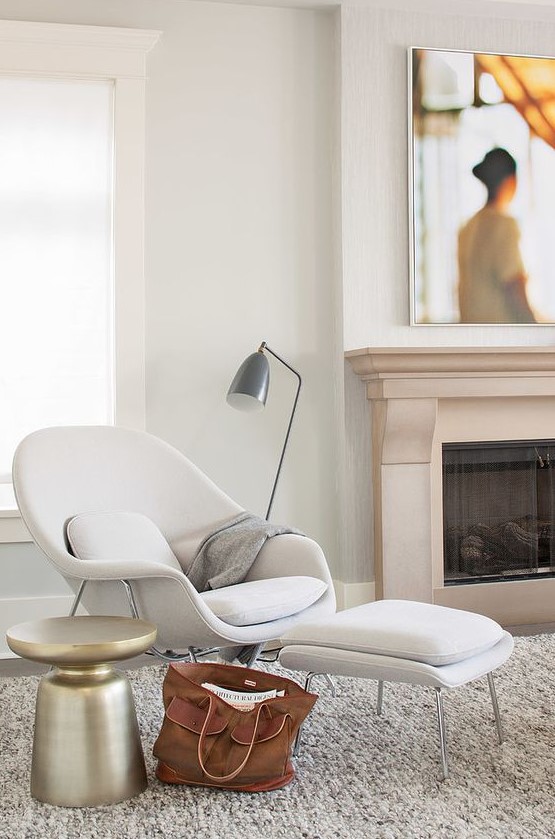 a comfy mid-century-inspired white chair and a matching footrest, a metal floor lamp and a metal side table for a comfy nook