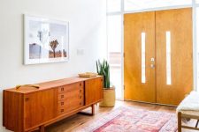 a cool rich-stained mid-century modern sideboard with drawers and doors, with small metal handles and on frame legs