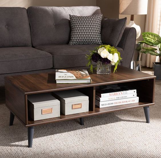 A dark stained storage coffee table on black tapered legs is a cool and chic idea for a mid century modern interior to rock