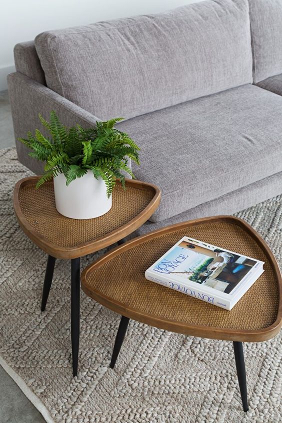a duo of rattan mid-century modern tables shaped as rounded triangles and with black tapered legs is a creative idea