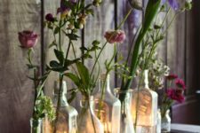 a framed mirror with vintage bottles and bright blooms plus candles is a cool decoration for any rustic or boho space
