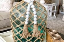 a green bottle with a twine net and whitewashed wooden beads is a cool decoration for a modern space