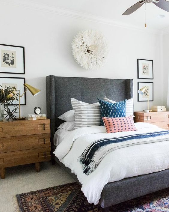 a grey upholstered bed with a curved headboard and rough wooden nightstands for a cozy feel