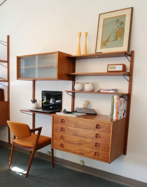 A large mid century modern wall unit with a compartment with a glass door, drawers, shelves and a tiny desk