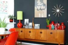 a light-stained mid-century modern cabinet with doors and black handles is a stylish idea for this bold dining room