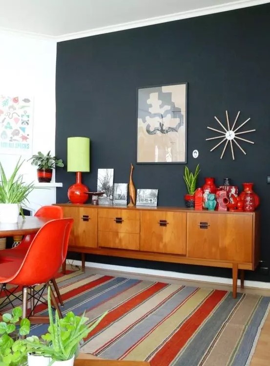 A light stained mid century modern cabinet with doors and black handles is a stylish idea for this bold dining room
