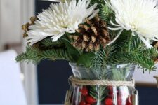 a lovely Christmas centerpiece of a vase with cranberries, evergreens, white blooms and gilded pinecones is easy to make