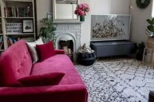 a lovely contemporary neutral living room with built-in shelves, a non-working fireplace, a hot pink loveseat, potted plants and a cool gallery wall