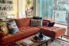 a lovely living room with a rust-colored mid-century modern sectional, a low table, floating shelves and potted plants here and there