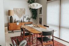 a lovely mid-century modern dining room with a credenza, a stained table, black chairs, a faceted pendant lamp and a bold printed rug
