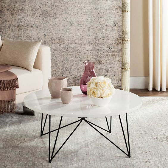 A mid century modern coffee table with a white round tabletop and black geometric legs is a great idea to rock